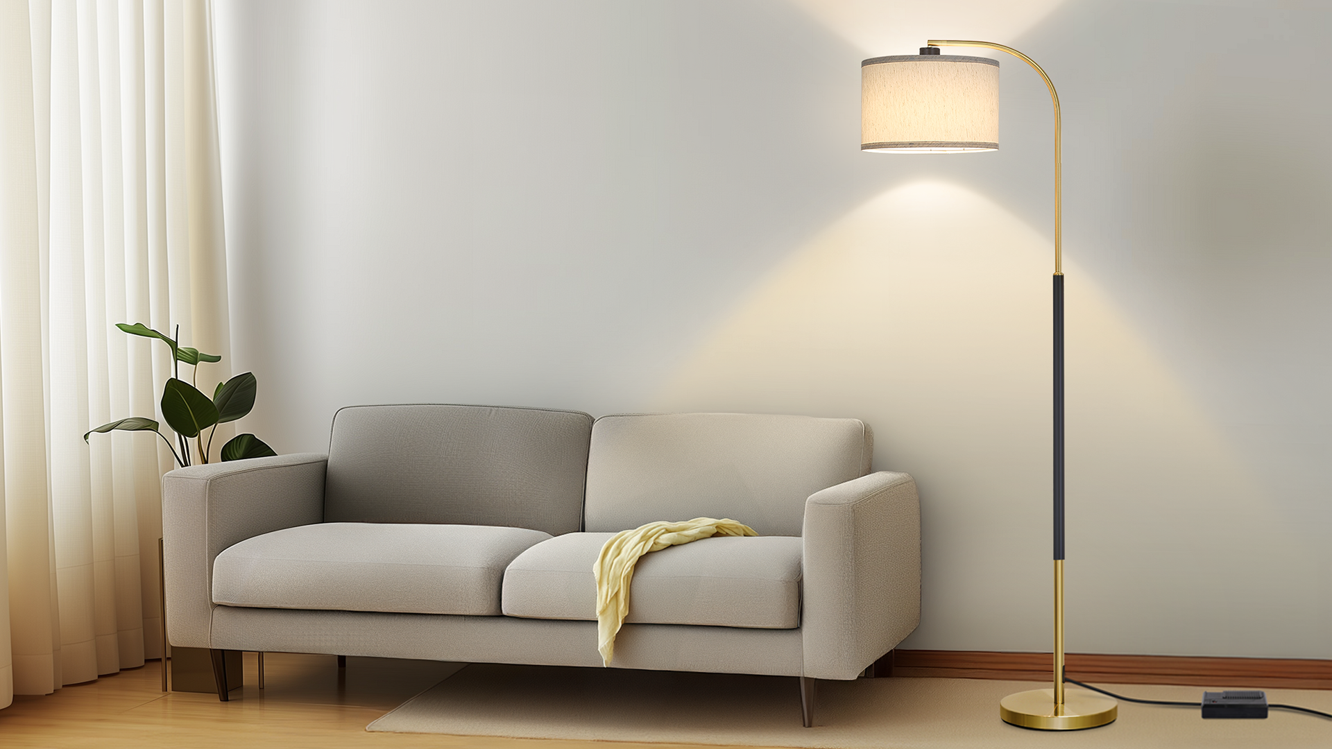 A tall floor lamp with a natural linen drum shade standing beside a sofa in a softly lit living room, real photo