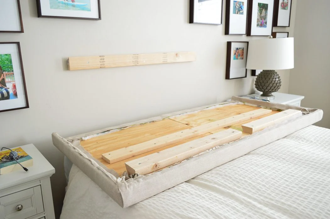 A tape measure showing a small gap between the top of a mattress and the bottom edge of an upholstered headboard