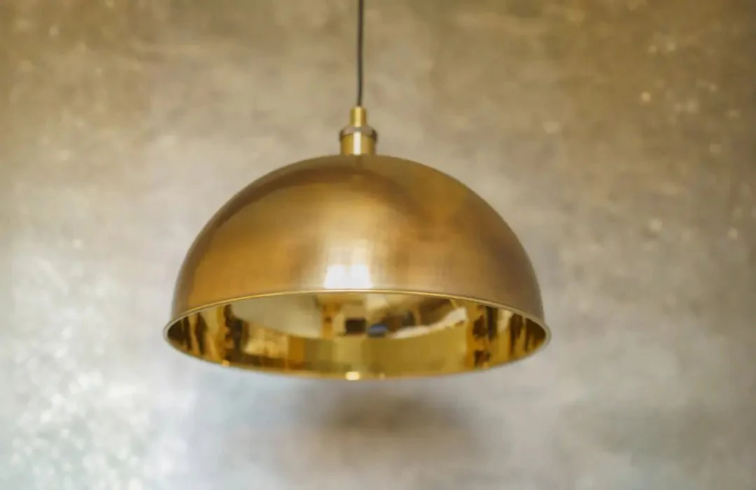 A warm kitchen with oil-rubbed bronze cabinet knobs, a single brass pendant light, and creamy cabinetry with wood countertops in golden evening light