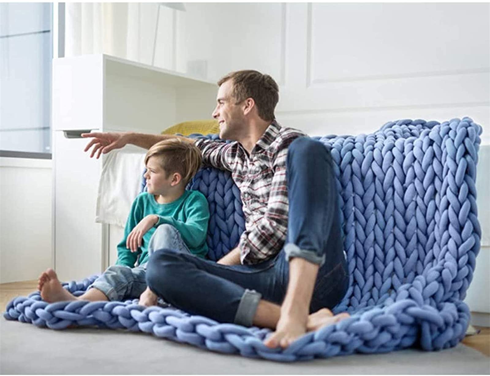 Chunky knit throw loosely folded on a neutral sofa with a warm brass floor lamp nearby