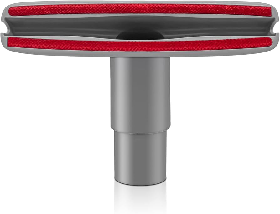 Close-up of a vacuum upholstery brush cleaning dust from the button tufts of a beige fabric headboard, natural light