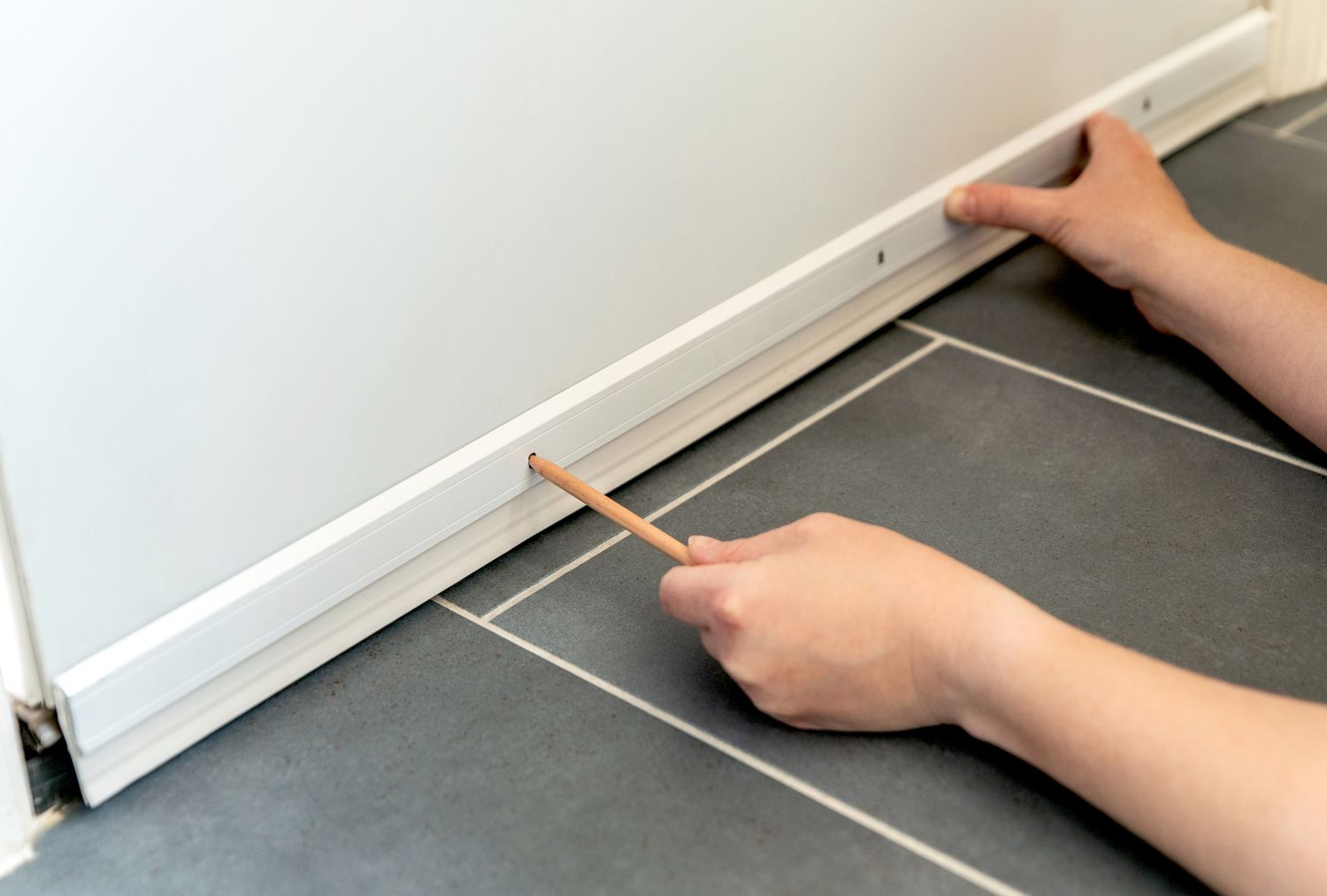 Close-up of an apartment bedroom door with a simple adhesive door sweep installed along the bottom edge, real-life home photo
