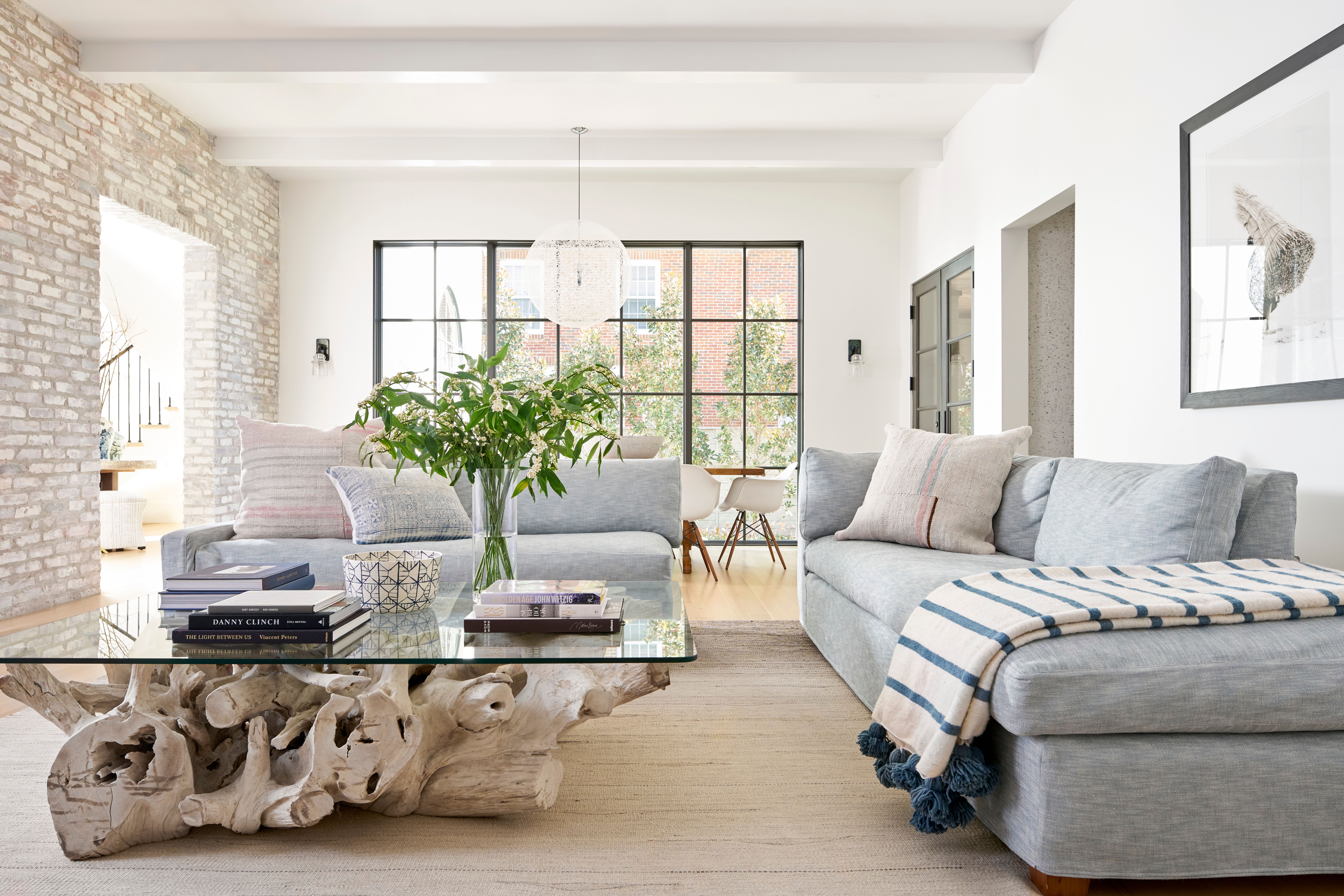 Cream and bright white fabric swatches held beside a gray sofa arm in natural light
