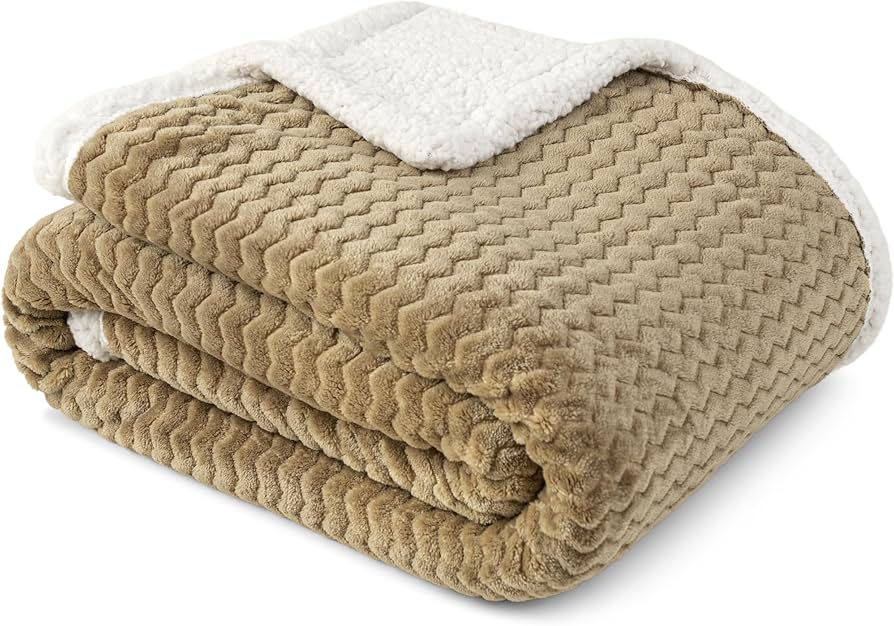 Cream wool throw with a visible weave draped over a sofa arm, paired with a linen pillow in soft daylight