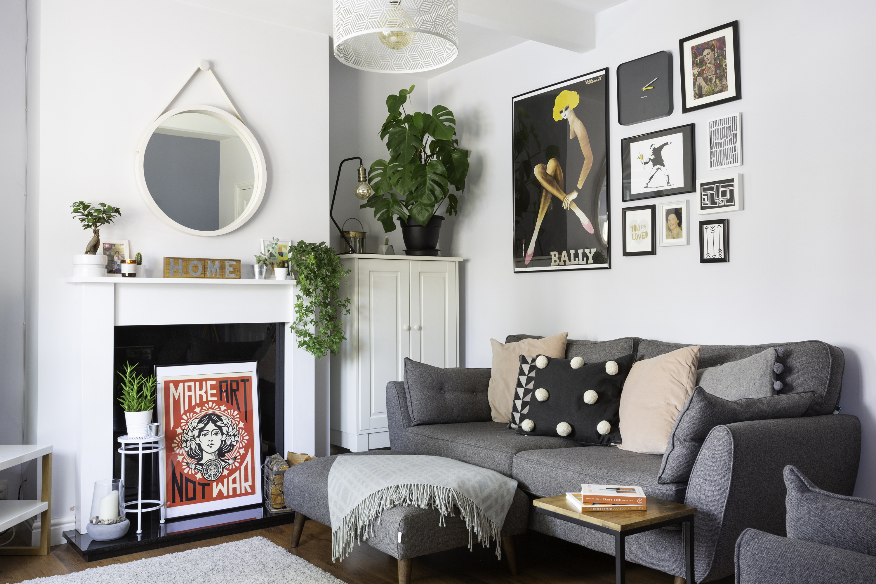 Gray sofa with a small gallery wall of warm-toned art in wood and brass frames, lit by a nearby lamp