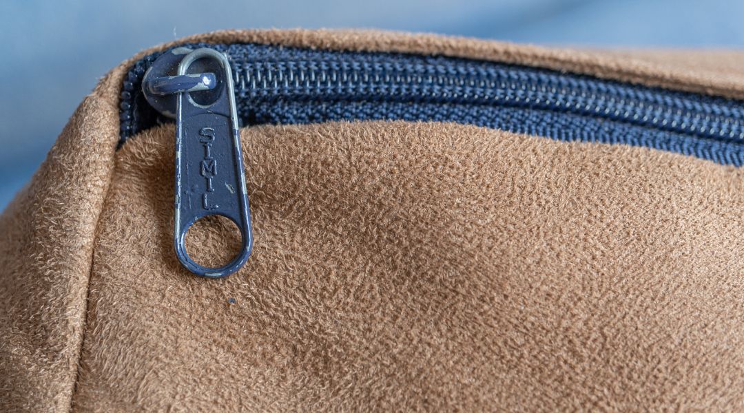 Hands unzipping a seat cushion cover and inspecting the inner insert near the seam in natural daylight