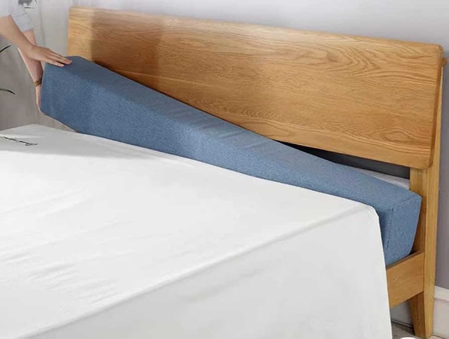 Hands using a tape measure to measure the distance between the top edge of a mattress and a fabric upholstered headboard in a bedroom