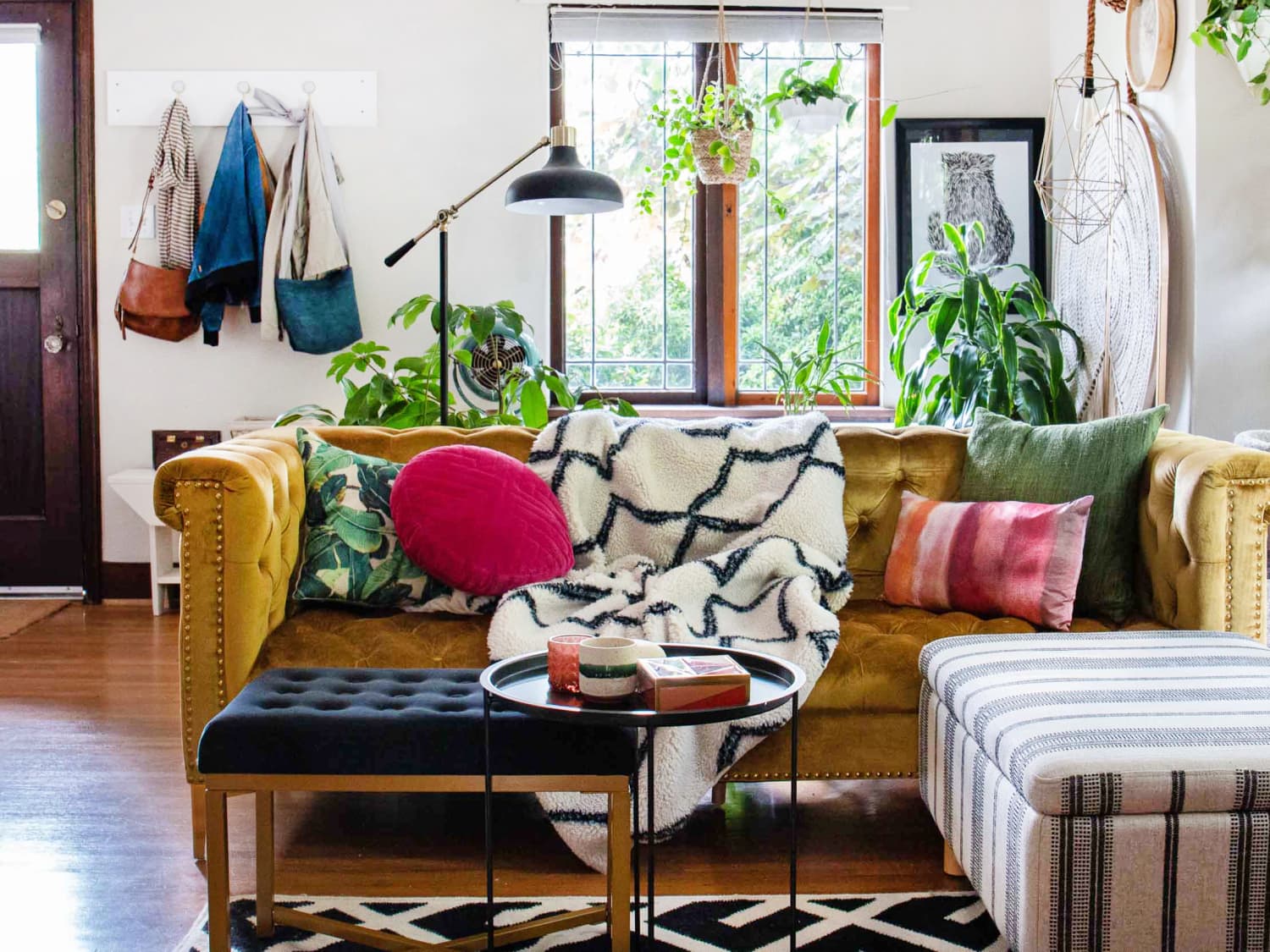 Living room corner with a vintage brass table lamp, a neutral sofa, and a textured throw draped over the cushion