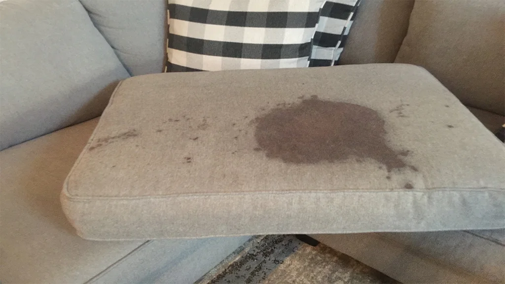 Melted chocolate smeared on a light beige fabric sofa cushion