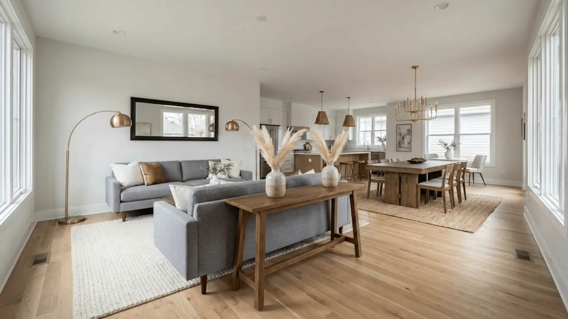 Open concept room using a large rug, pendant light over a dining table, and table lamps in the living area to define separate zones