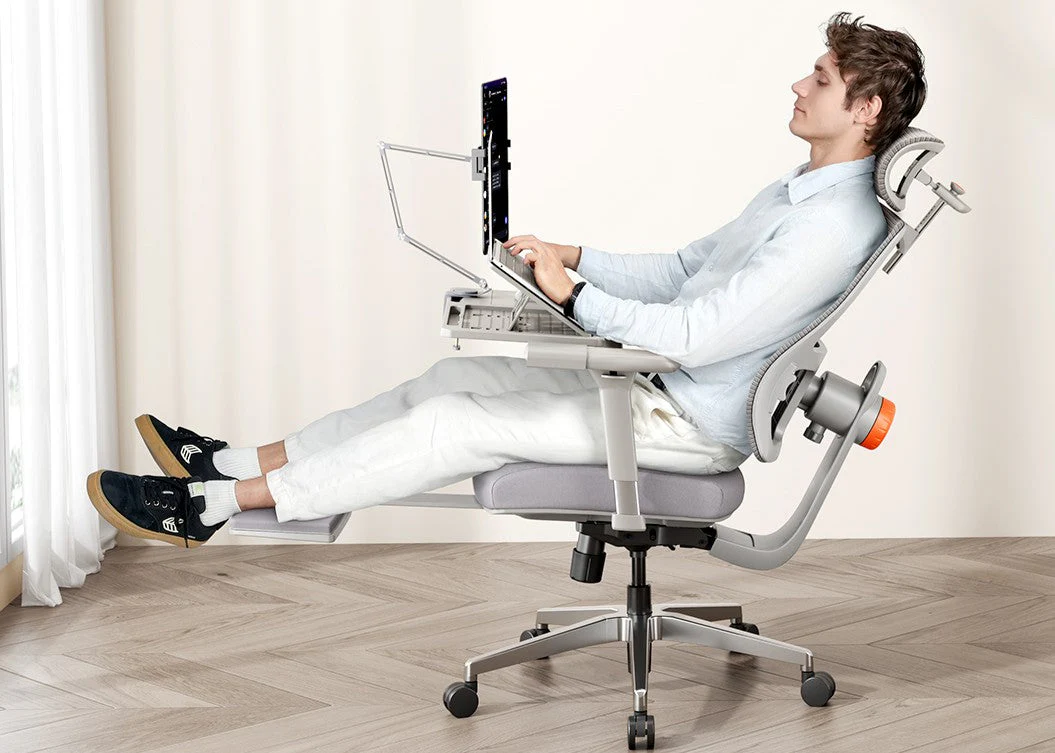 Two people in a living room gently rocking a loveseat while one person feels along the underside frame to locate a squeak, candid home photo